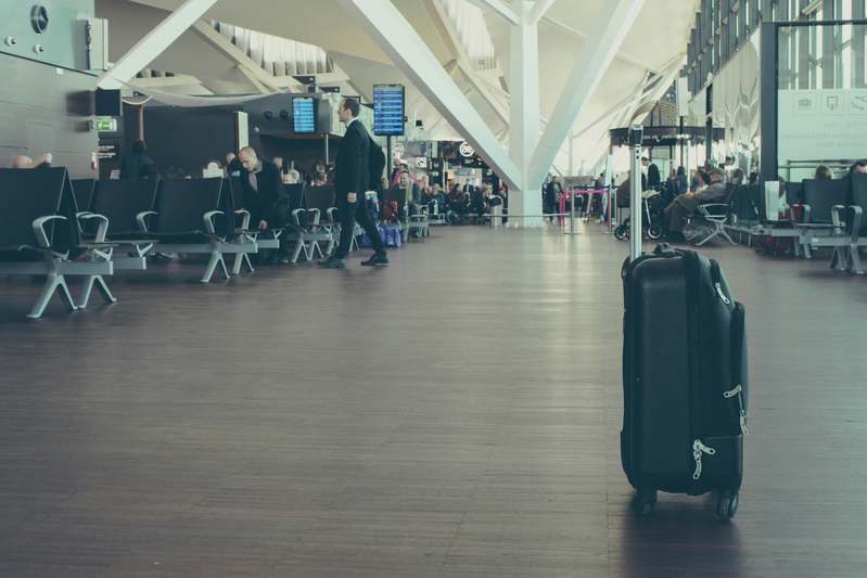 Woman reading travel insurance documents beside open suitcase in hotel room